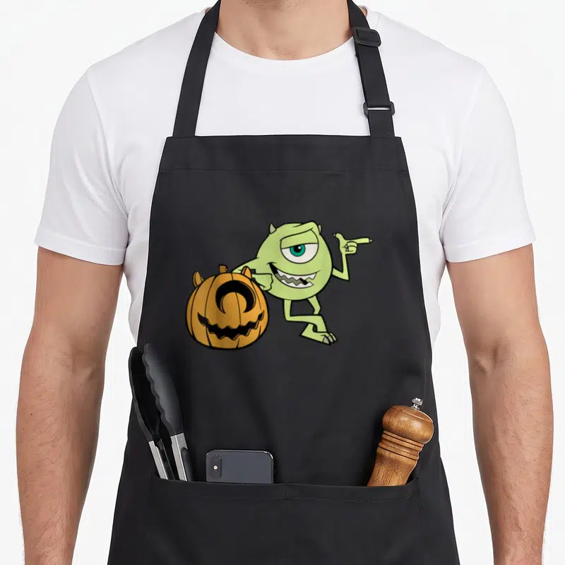 Tablier de cuisine noir avec Mike vert pointant vers une pumpkin orange souriante.