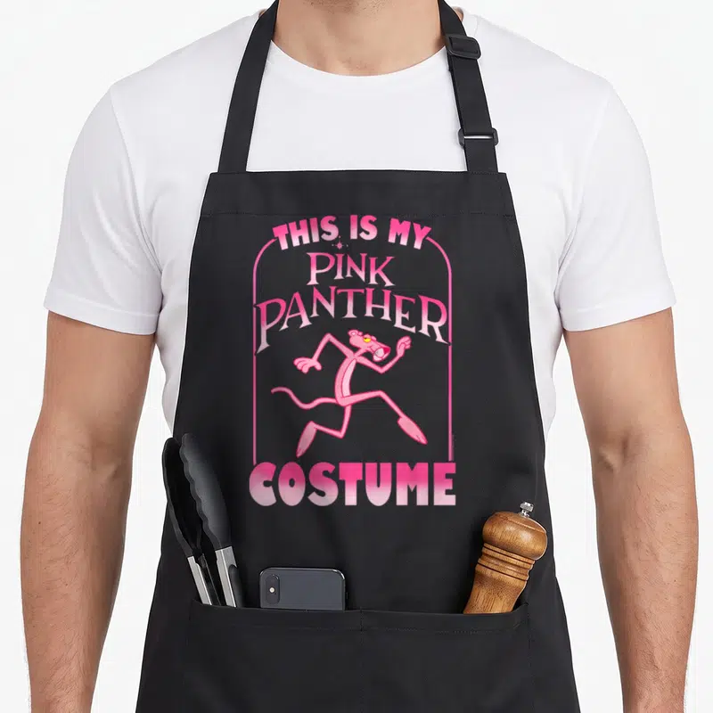 Tablier de cuisine noir avec une illustration rose de la Panthère Rose et du texte en anglais.