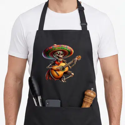 Tablier de cuisine noir avec squelette mariachi jouant de la guitare sous un grand sombrero multicolore.