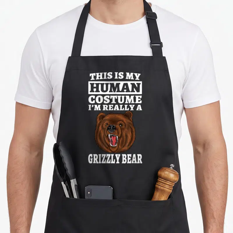 Tablier de cuisine noir avec tête de grizzly rugissant et texte blanc en anglais.