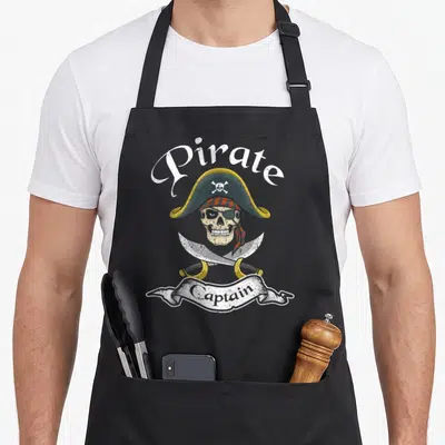 Tablier de cuisine noir avec un crâne de pirate en chapeau et deux sabres croisés sous le mot Captain.