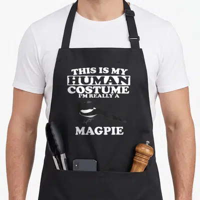 Tablier de cuisine noir avec illustration d'un magpie et texte blanc C'est mon costume humain.