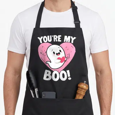 Tablier de cuisine noir avec un fantôme blanc tenant un cœur rouge devant un grand cœur rose et le texte You're My Boo.