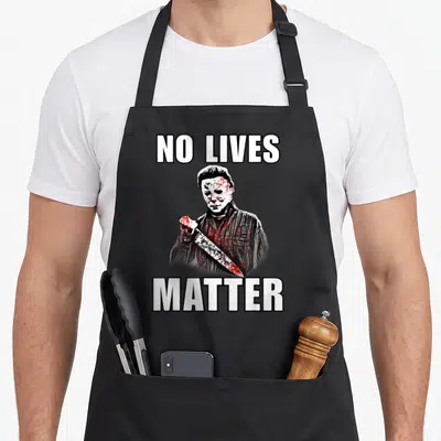 Tablier de cuisine noir avec illustration d'un homme masqué tenant un couteau et le texte No Lives Matter en blanc.