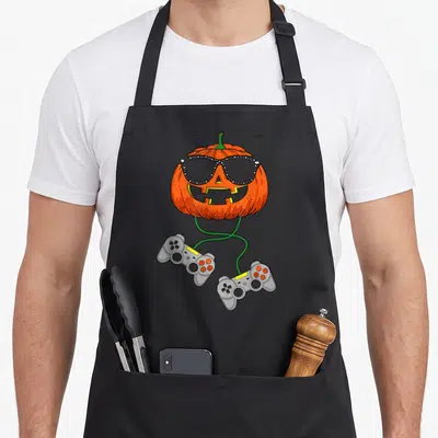Tablier de cuisine noir avec une citrouille gamer portant des lunettes et tenant deux manettes de jeu vidéo.