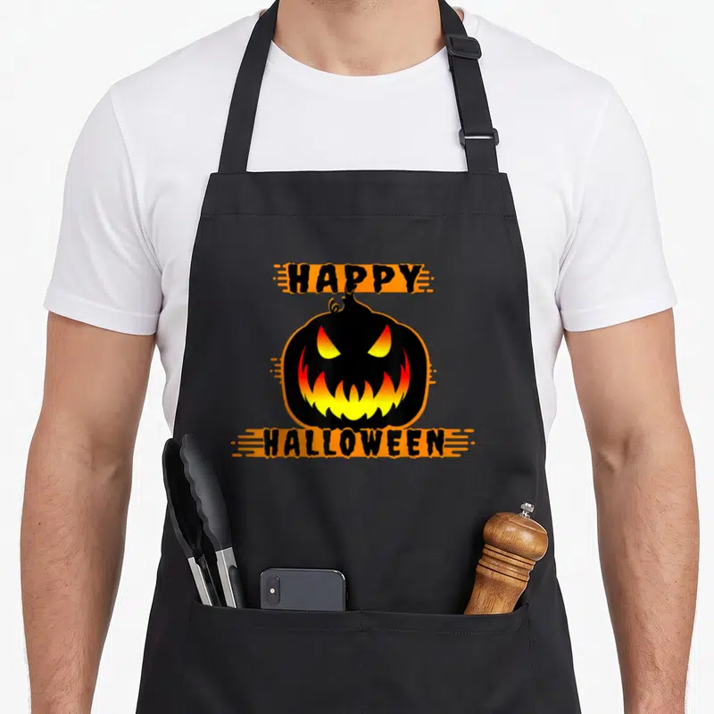 Tablier de cuisine noir avec citrouille Halloween orange et texte Happy Halloween imprimé en noir.