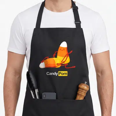 Tablier de cuisine noir avec deux bonbons cornes orange jaunes en position suggestive et le texte Candy Porn imprimé en dessous.