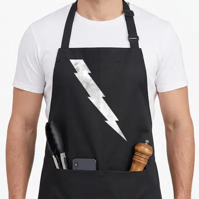 Tablier de cuisine noir avec une grande foudre blanche texturée en diagonale sur le devant.