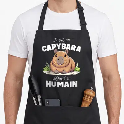 Tablier de cuisine noir avec illustration d'un capybara et texte blanc Je suis un Capybara déguisé en Humain