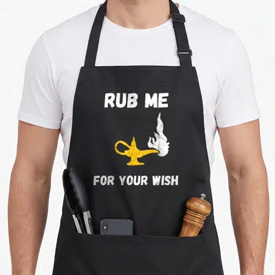 Tablier de cuisine noir avec illustration de lampe de génie jaune et texte blanc Rub Me For Your Wish.