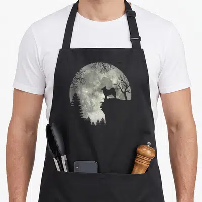 Tablier de cuisine noir avec une lune contenant une silhouette de chien et des arbres en double exposition.