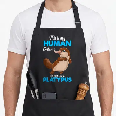 Tablier de cuisine noir avec illustration d'un ornithorynque et texte C'est Mon Costume Humain Je Suis Vraiment Un Ornithorynque en bleu et blanc.