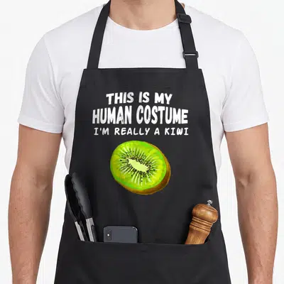 Tablier de cuisine noir avec illustration de kiwi et texte blanc humoristique sur le devant.
