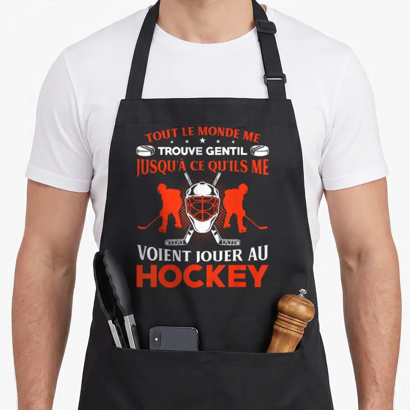 Tablier de cuisine noir avec casque de hockey,ettes et texte humoristique en blanc et orange.