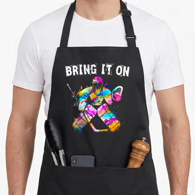 Tablier de cuisine noir avec illustration d'un gardien de hockey sur glace multicolore et le texte Bring It On en blanc.