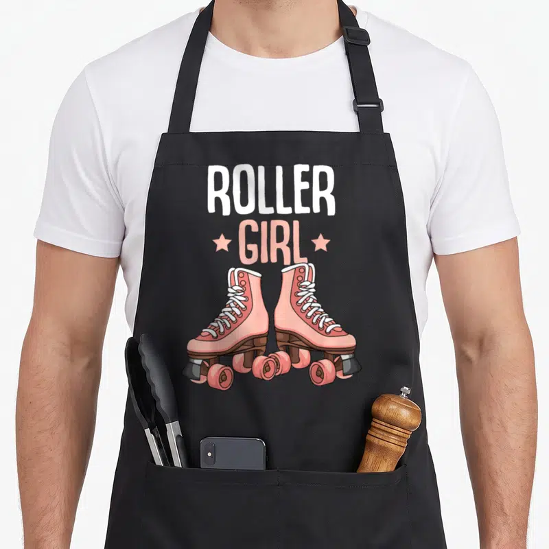 Tablier de cuisine noir avec illustration de patins à roulettes roses et texte ROLLER GIRL en blanc et rose.