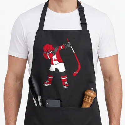 Tablier de cuisine noir avec un joueur de hockey Canada Ice Hockey en tenue rouge et blanche effectuant la pose Dabbing avec une crosse.