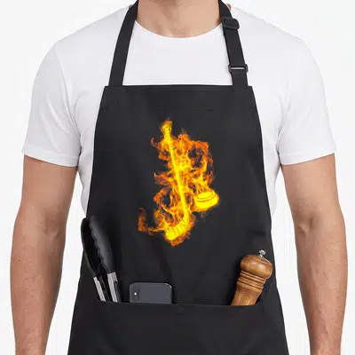 Tablier de cuisine noir avec un bâton de hockey et une rondelle enveloppés de flammes orange vif.