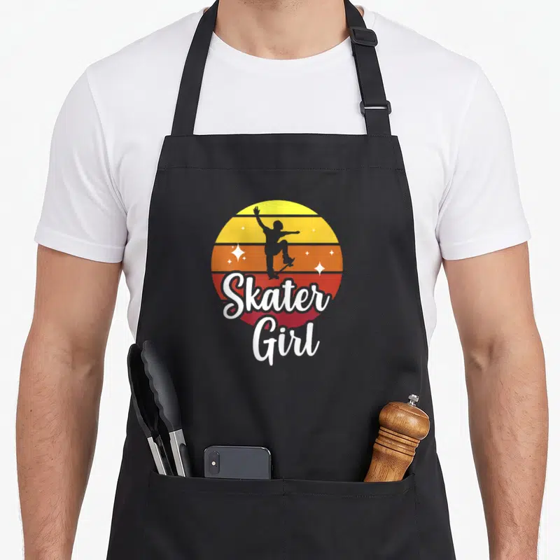 Tablier de cuisine noir avec illustration Skater Girl skateboard et soleil rétro coloré.