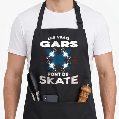 Tablier de cuisine noir avec inscription Les Vrais Gars Font Du Skate et planches de skateboard croisées.