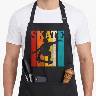 Tablier de cuisine noir avec silhouette de skater et texte SKATE sur bandes colorées vintage.