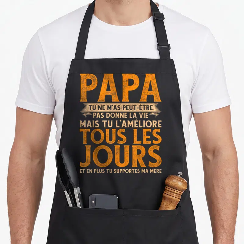 Tablier de cuisine noir avec inscription orange et blanche Papa tu ne m'as peut-être pas donné la vie mais tu l'améliores tous les jours.