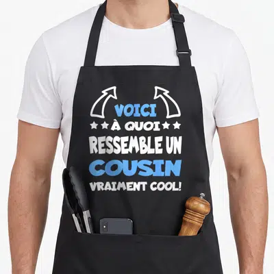 Tablier de cuisine noir avec inscription voici à quoi ressemble un cousin vraiment cool en lettres blanches et bleues.
