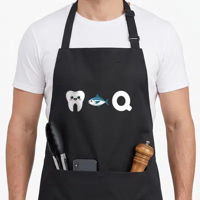 Tablier de cuisine noir avec une illustration d'une dent blanche souriante, d'un thon bleu et de la lettre Q en blanc.
