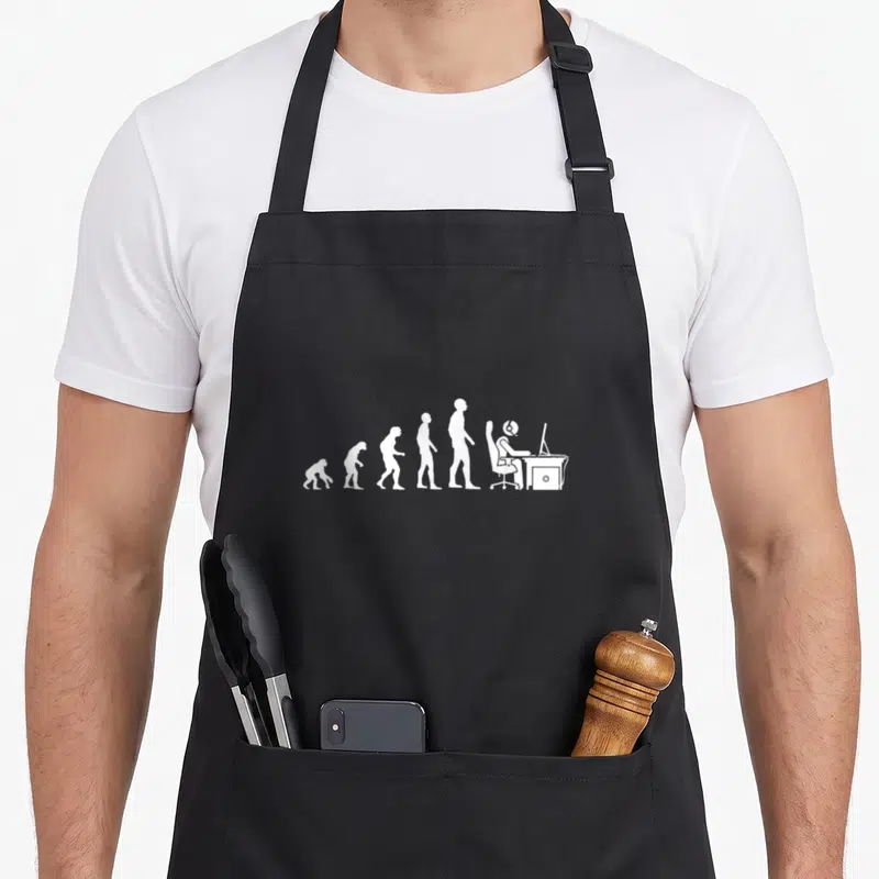 Tablier de cuisine noir avec une illustration blanche représentant l'évolution humaine se terminant par un individu assis devant un ordinateur.