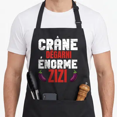 Tablier de cuisine noir avec texte blanc et rouge crâne dégarni enormous zizi et deux aubergines violettes.