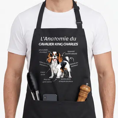 Tablier de cuisine noir avec illustration anatomique humoristique d'un chien cavalier king charles et ses organes fictifs.