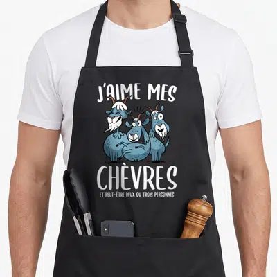 Tablier de cuisine noir avec trois chèvres bleues stylisées et le texte blanc J'aime mes chèvres et peut-être deux ou trois personnes.