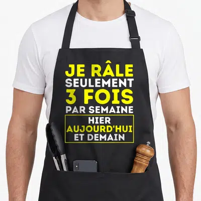 Tablier de cuisine noir avec l'inscription Je râle seulement 3 fois par semaine hier aujourd'hui et demain en jaune et blanc.