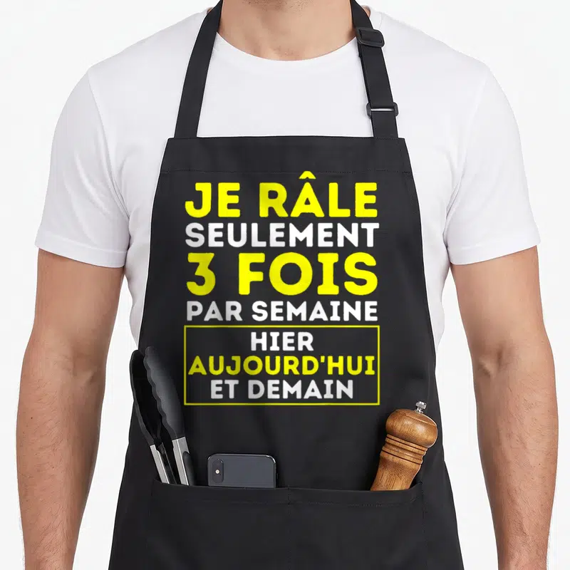 Tablier de cuisine noir avec l'inscription Je râle seulement 3 fois par semaine hier aujourd'hui et demain en jaune et blanc.