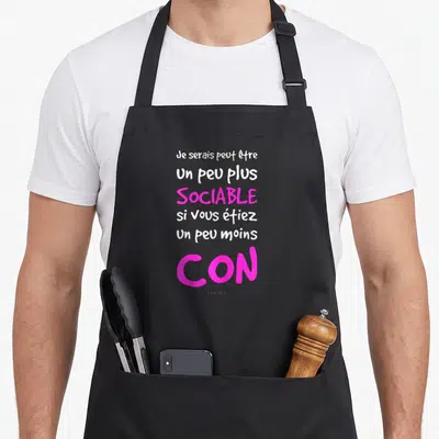 Tablier de cuisine noir avec une citation humoristique en blanc et rose vif sur fond uni.