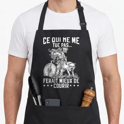 Tablier de cuisine noir avec illustration d'un guerrier viking, d'un loup et du texte Ce qui ne me tue pas ferait mieux de courir.