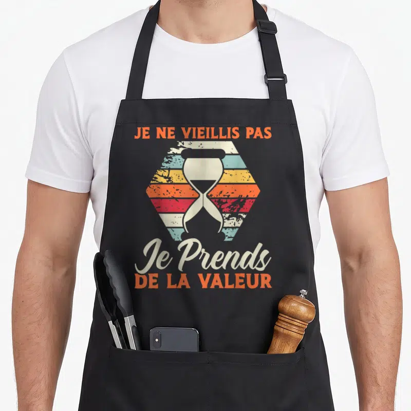 Tablier de cuisine noir avec illustration hexagonale colorée et sablier central sur fond uni.