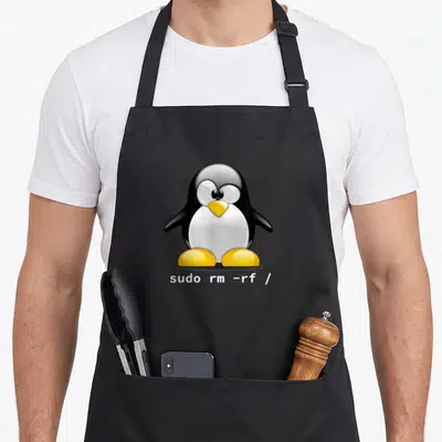 Tablier de cuisine noir avec l'illustration de Tux le pingouin et la commande sudo rm -rf / en blanc sous ses pieds.