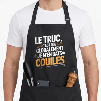 Tablier de cuisine noir avec le truc c'est que globalement je m'en bats les couilles imprimé en blanc et orange.