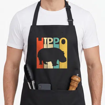 Tablier de cuisine noir avec silhouette d'hippopotame gris devant le mot HIPPO en lettres verticales orange, jaune et turquoise.