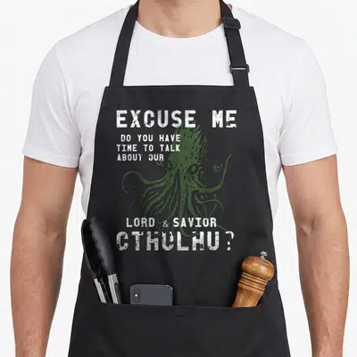 Tablier de cuisine noir avec illustration verte de Cthulhu et texte blanc humoristique sur fond uni.