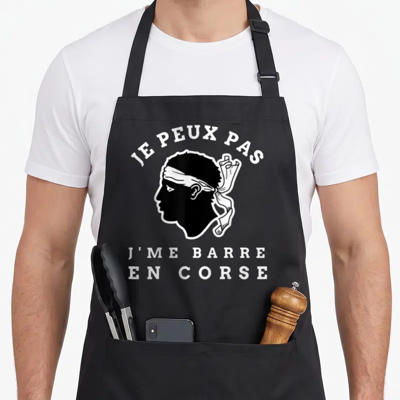 Tablier de cuisine noir avec silhouette corse et texte blanc Je peux pas jme barre en corse