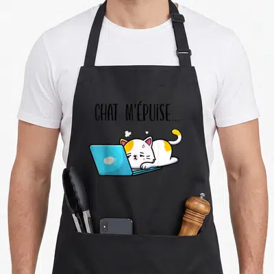 Tablier de cuisine noir avec illustration d'un chat blanc et orange fatigué devant un ordinateur bleu et le texte chat m'épuise.