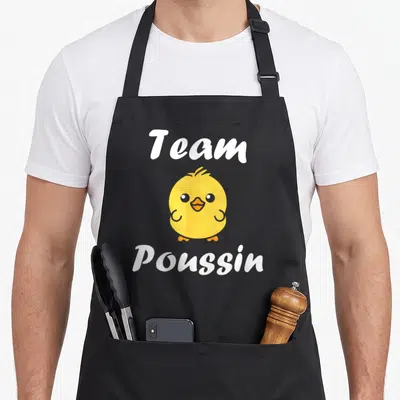 Tablier de cuisine noir avec un petit poussin jaune rond et le texte blanc Team Poussin imprimé au centre.