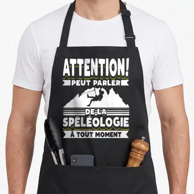Tablier de cuisine noir avec inscription attention peut parler de la spéléologie à tout moment et silhouette d'un spéléologue en cordage.