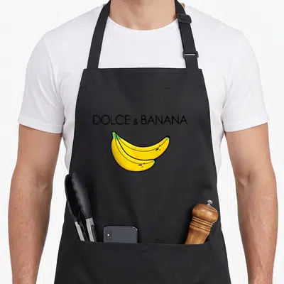 Tablier de cuisine noir avec l'inscription Dolce et Banana et deux bananes jaunes illustrées au centre.