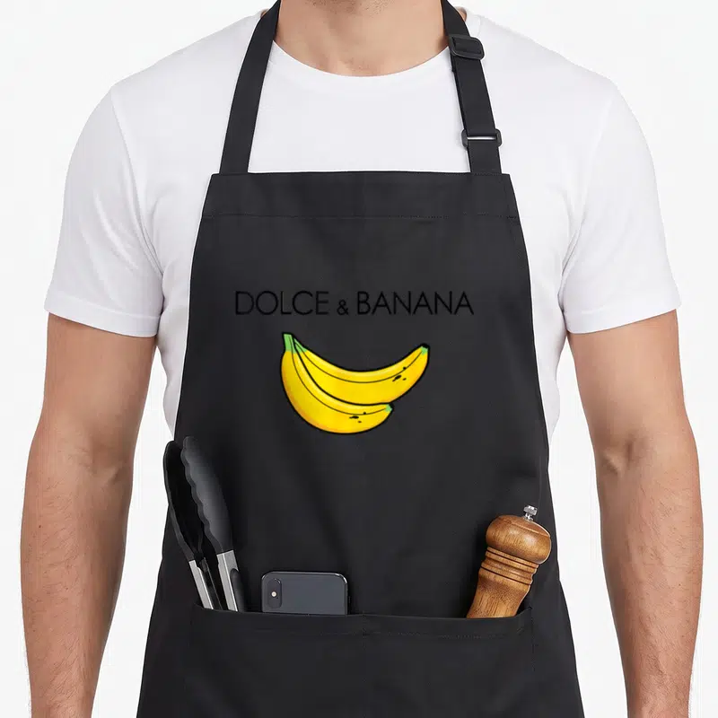 Tablier de cuisine noir avec l'inscription Dolce et Banana et deux bananes jaunes illustrées au centre.