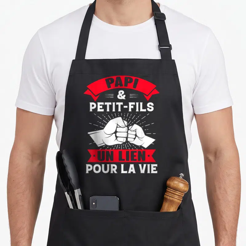 Tablier de cuisine noir avec deux poings se serrant et le texte Papi et Petit-Fils un lien pour la vie en blanc et rouge.