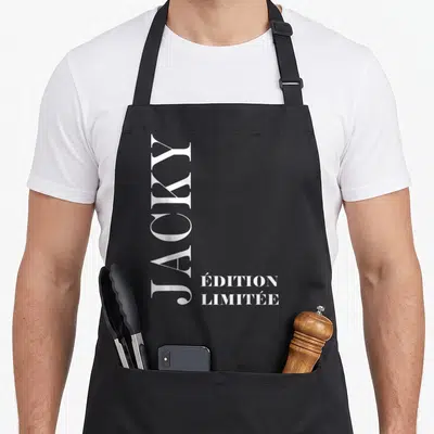 Tablier de cuisine noir avec le prénom Jacky écrit verticalement en blanc et la mention « édition limitée » en bas à droite.