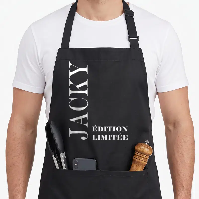 Tablier de cuisine noir avec le prénom Jacky écrit verticalement en blanc et la mention « édition limitée » en bas à droite.